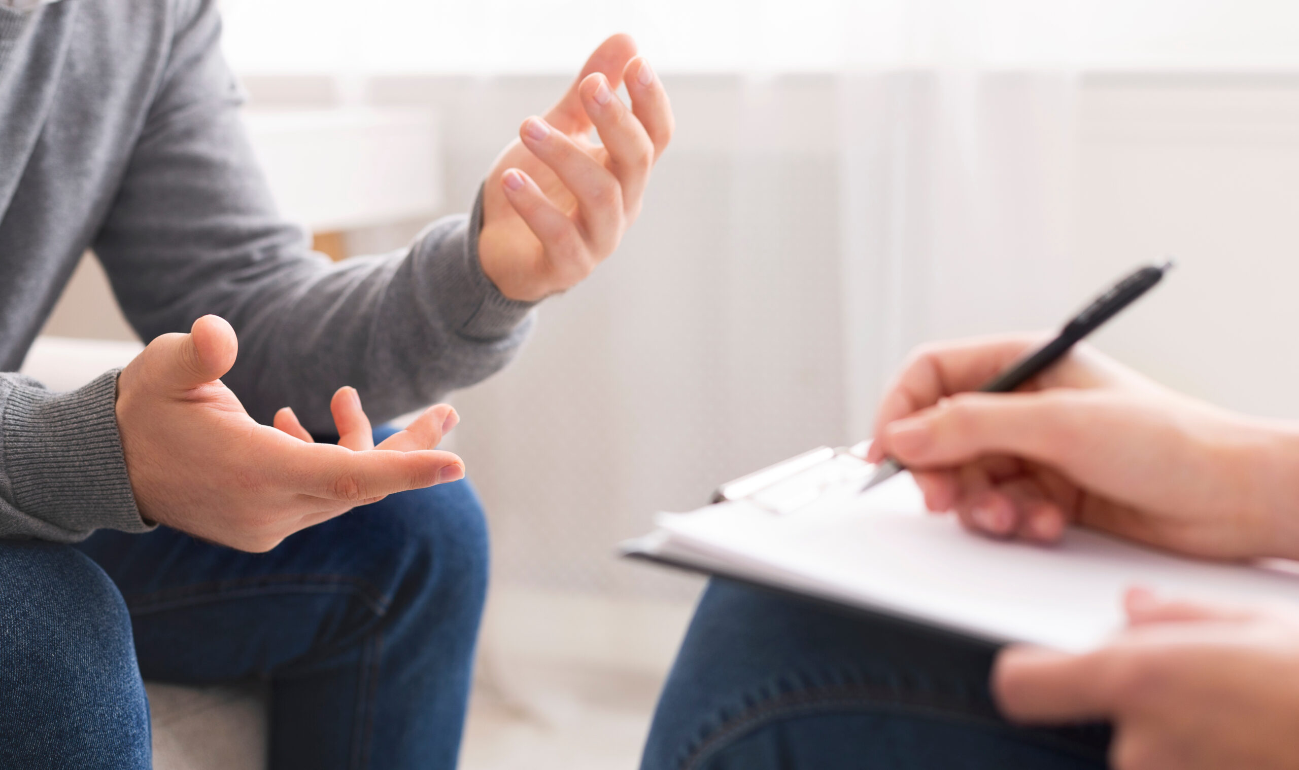 Psychotherapist writing notes, assessing patient's health and giving diagnosis to man sitting on couch during counseling session , panorama, free space